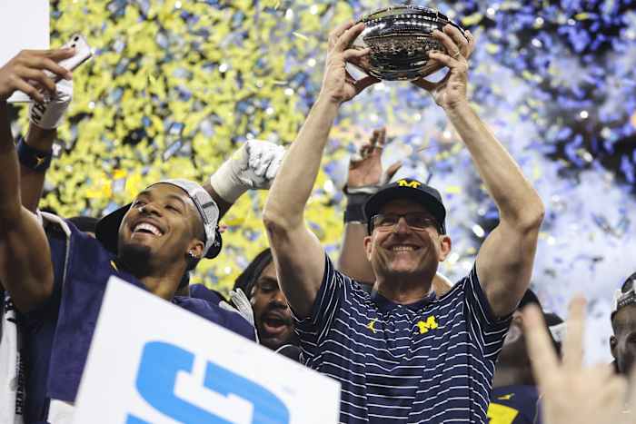 Michigan Wolverines head coach Jim Harbaugh raises the championship trophy following their 43-22 victory against Purdue in the Big Ten Championship at Lucas Oil Stadium.